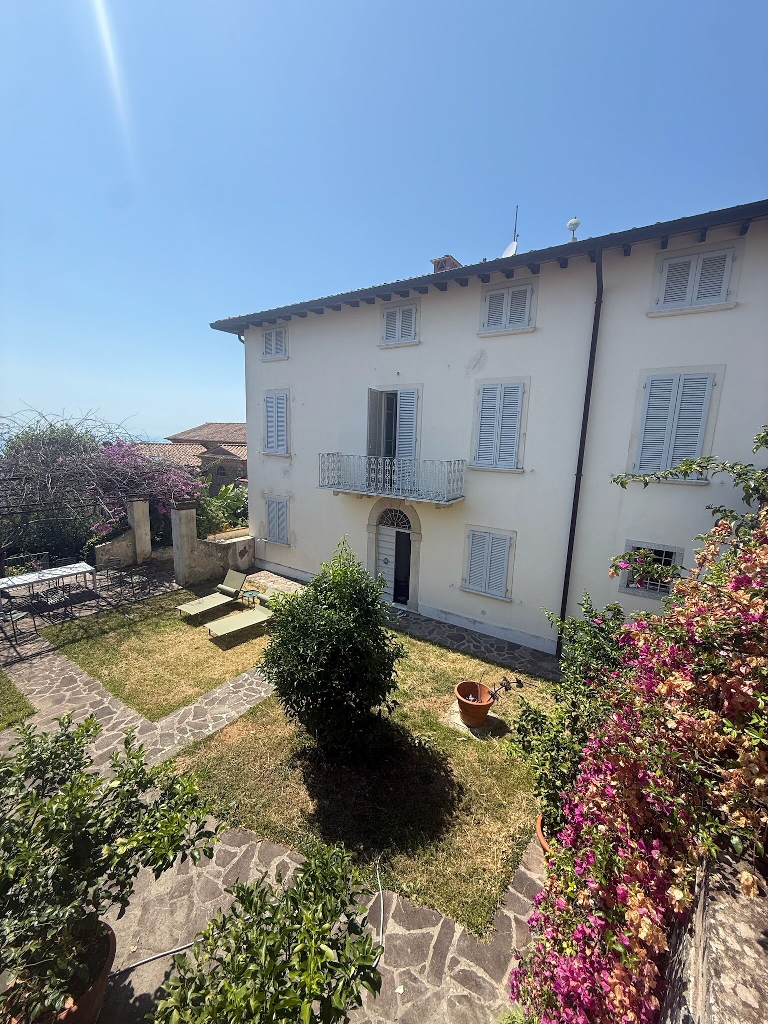 A two-story building with a stone patio, a small garden, and a balcony.