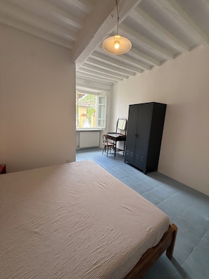 A bedroom with a bed, a wardrobe, a chair, and a window. - Stylish, high-end villa in the hills of Versilia with ocean views (Toscana)