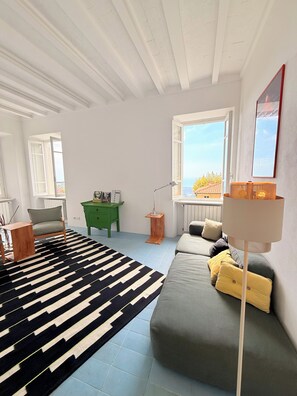 A modern living room with a sofa, a black and white rug, a green side table, and a lamp. - Stylish, high-end villa in the hills of Versilia with ocean views (Toscana)