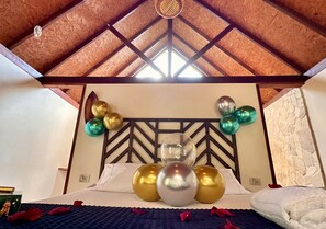Een kamer met een bed, een decoratief hoofdeinde en ballonnen.