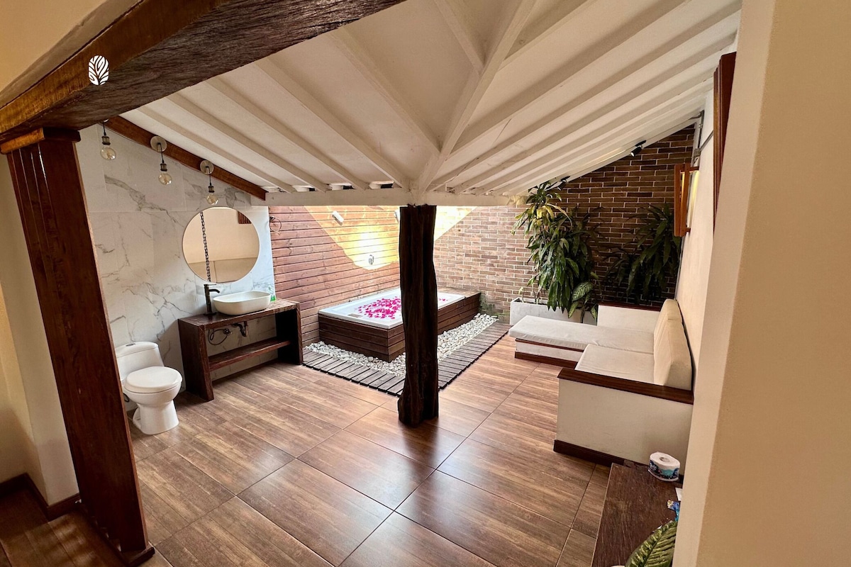 Een moderne badkamer met een houten vloer, een wit wastafelmeubel, een grote spiegel en een houten bankje.
