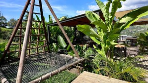 A wooden structure with a slatted floor, surrounded by lush greenery and a clear sky. - All Natural Glamping (Copacabana)