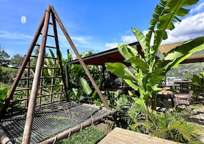 Een houten constructie met een gesloten vloer, omgeven door weelderige begroeiing en een heldere lucht.