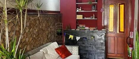 A cozy room with a sofa, a stone accent wall, a wooden door, and a shelf with various items.