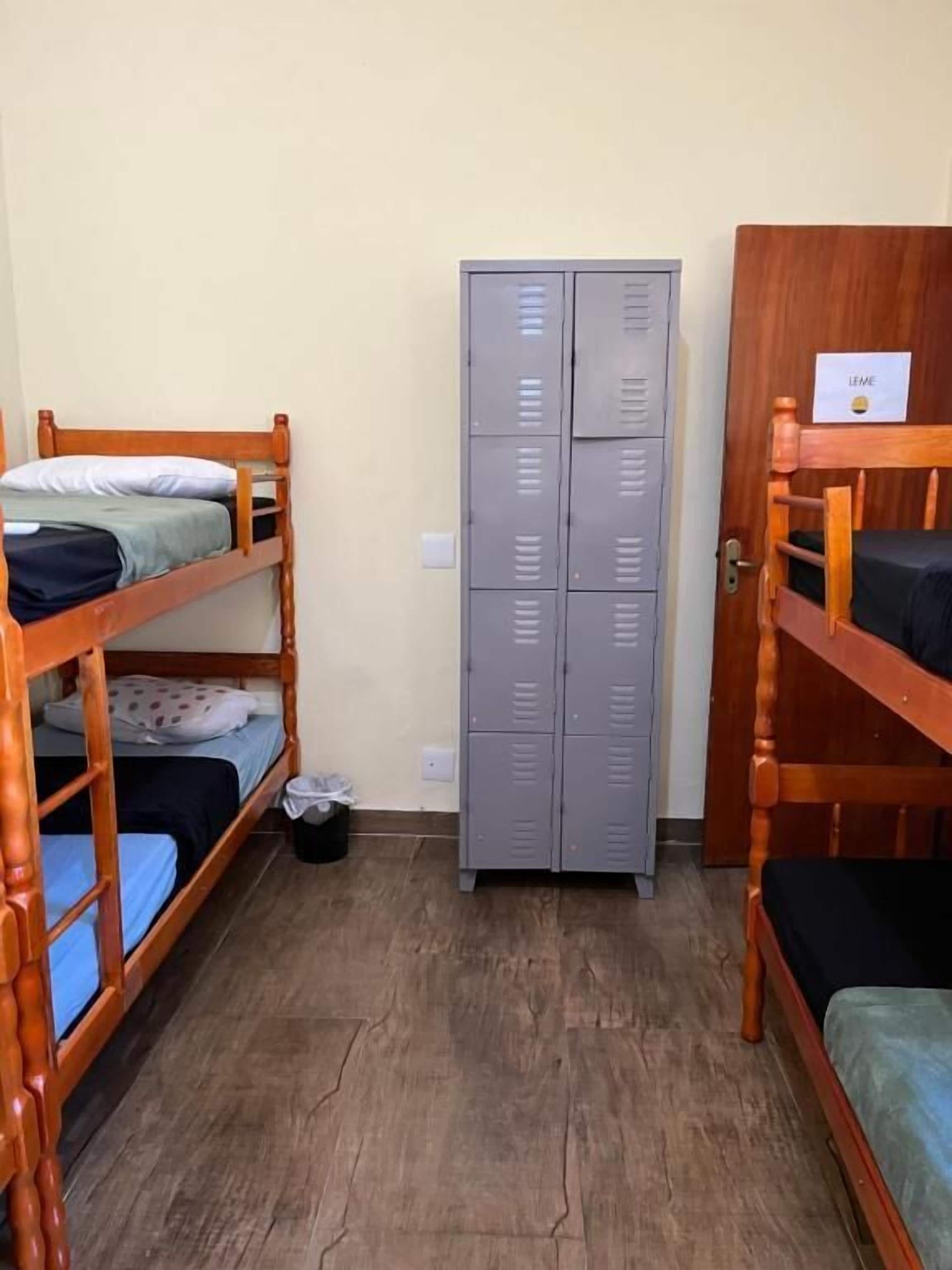 Quarto de dormitório com beliches, um guarda-roupa e uma porta com a etiqueta 'LIME'.