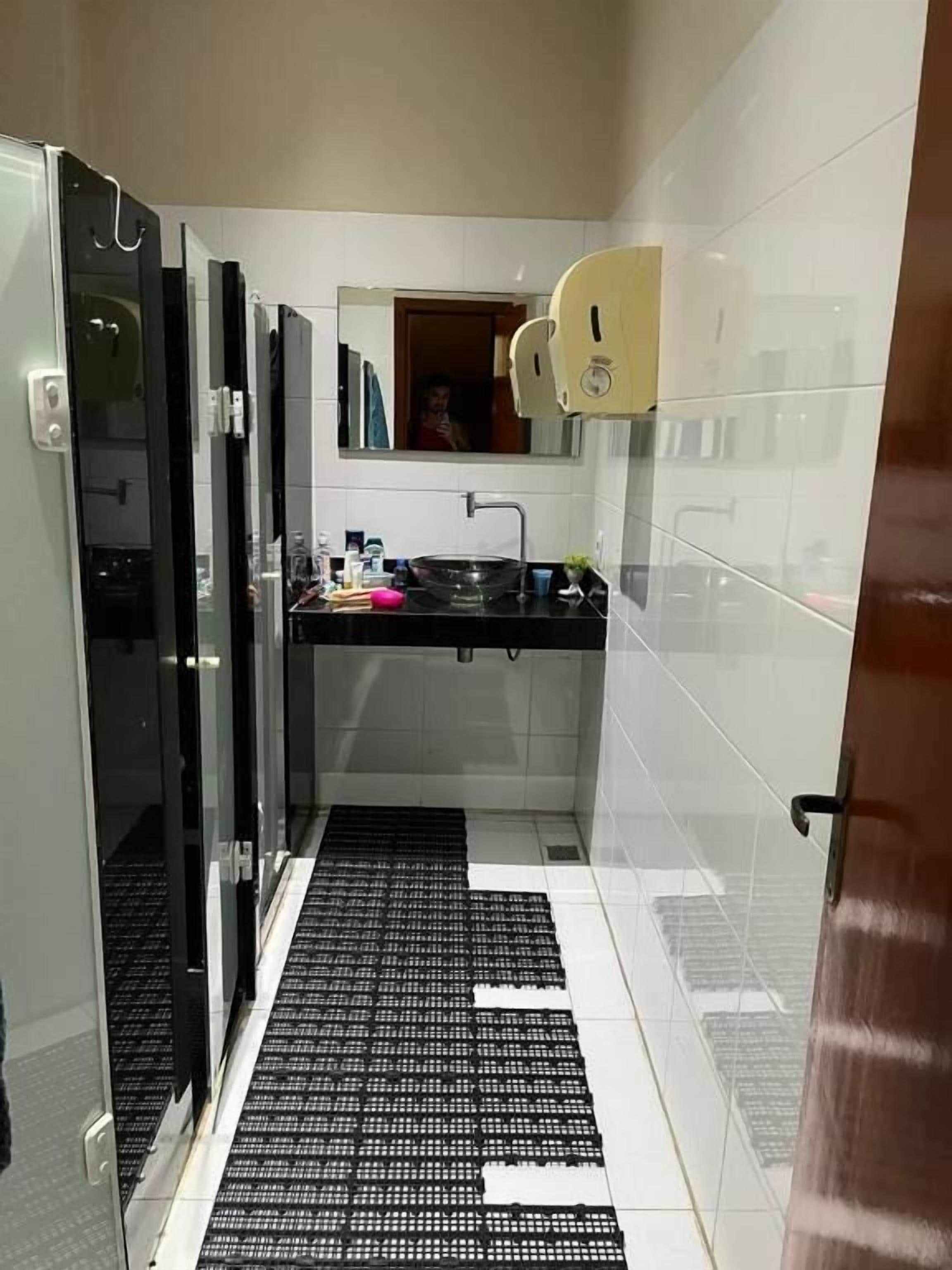 Casa de banho moderna com cabine de duche em vidro, lavatório preto e espelho sobre o lavatório.