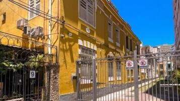 Um edifício amarelo com portão gradeado, placa indicando o número 9 e cerca de metal.