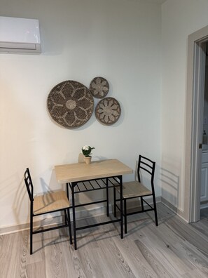 A dining area with a table and chairs, a potted plant, and decorative wall art. - 205 Bright Studio near Hospitals and Downtown (Indianapolis)