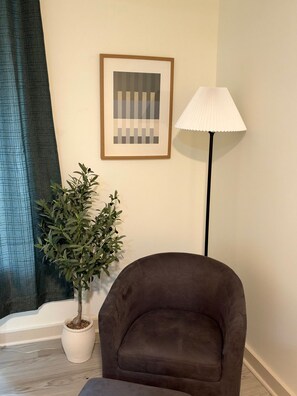 A room with a brown armchair, a potted plant, a framed picture, and a floor lamp. - 205 Bright Studio near Hospitals and Downtown (Indianapolis)
