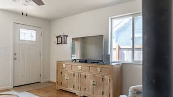 A room with a wooden cabinet, a television, a door, and a window.