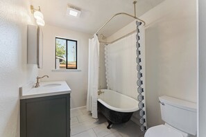 Casa de banho com banheira, sanita, lavatório e janela.