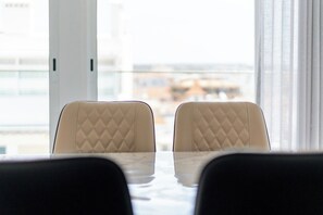 A view of a dining area with two chairs and a table, with a cityscape visible through a large window. - Algarve Oceanfront Luxury Penthouse (Armação de Pêra)