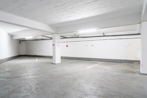 A parking garage with white walls, concrete floors, and visible structural beams. - Algarve Oceanfront Luxury Penthouse (Armação de Pêra)