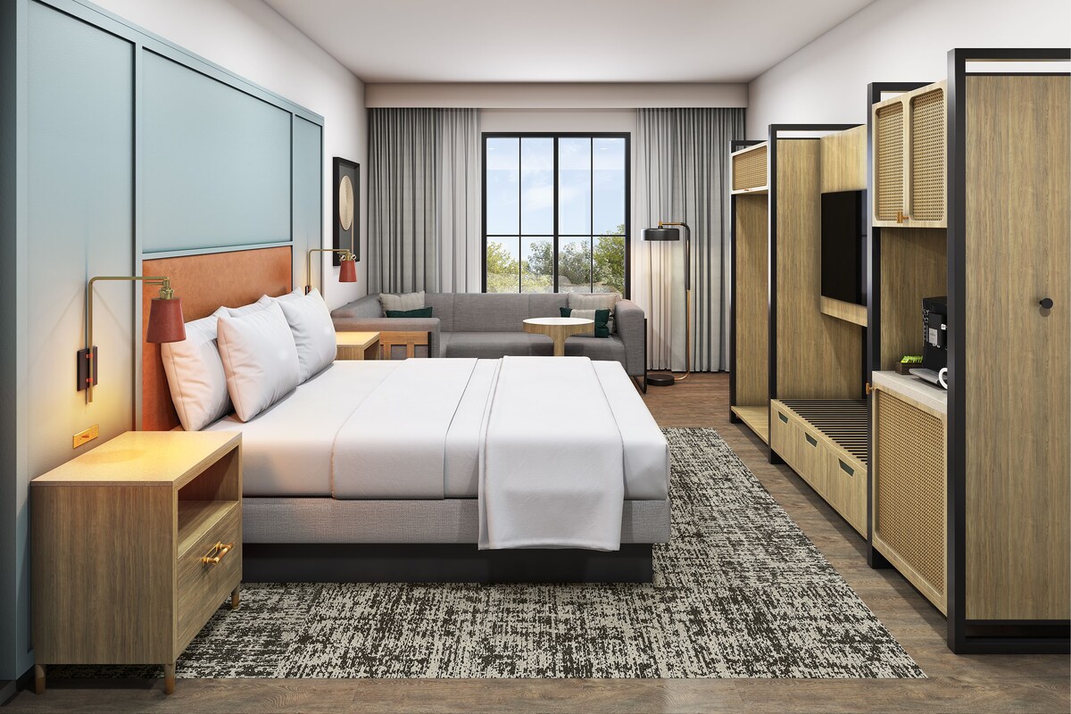 Una habitación de hotel moderna con una cama grande, un sofá, un escritorio y una televisión.