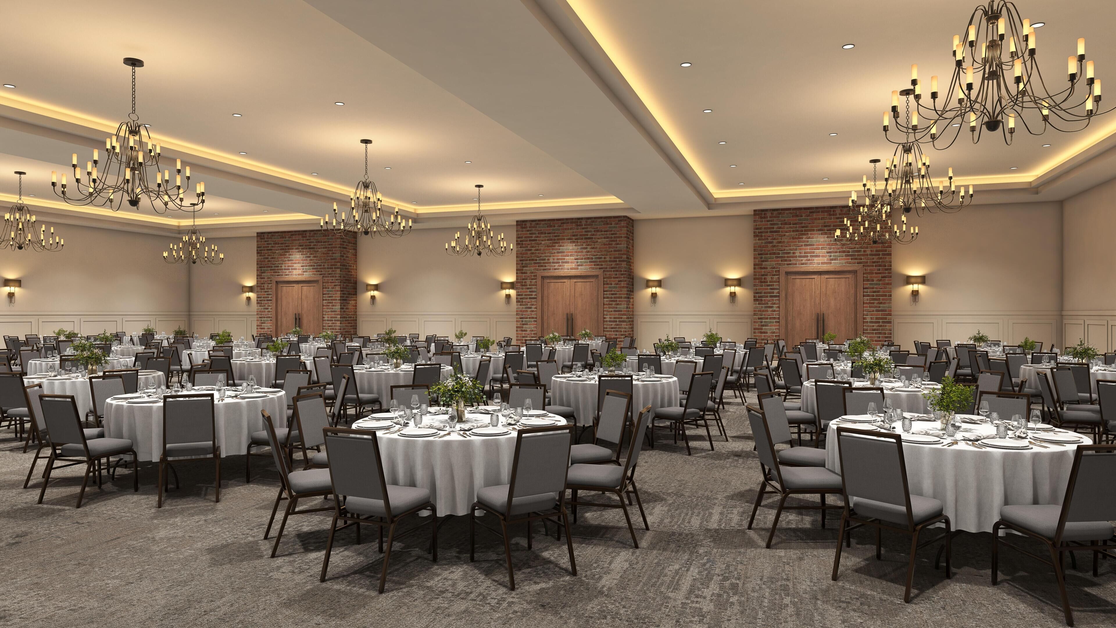 A banquet hall with round tables, chairs, chandeliers, and brick walls.