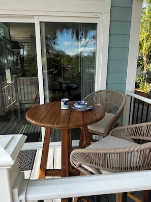Een houten tafel met twee stoelen en een glazen deur die uitkomt op een buitenruimte.