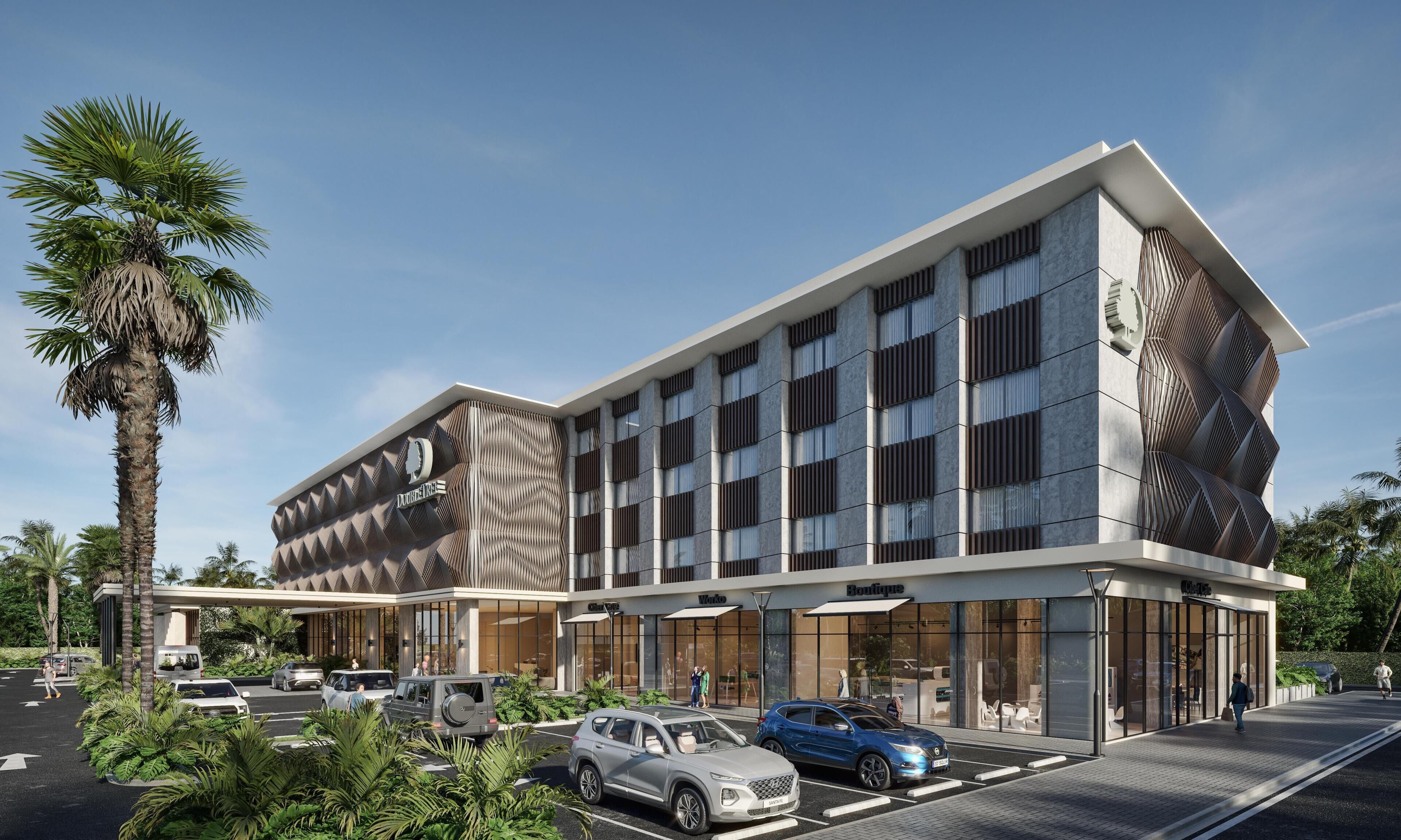 Un hôtel moderne à la façade originale, doté de nombreux espaces de stationnement et d’une entrée agrémentée d’un aménagement paysager.