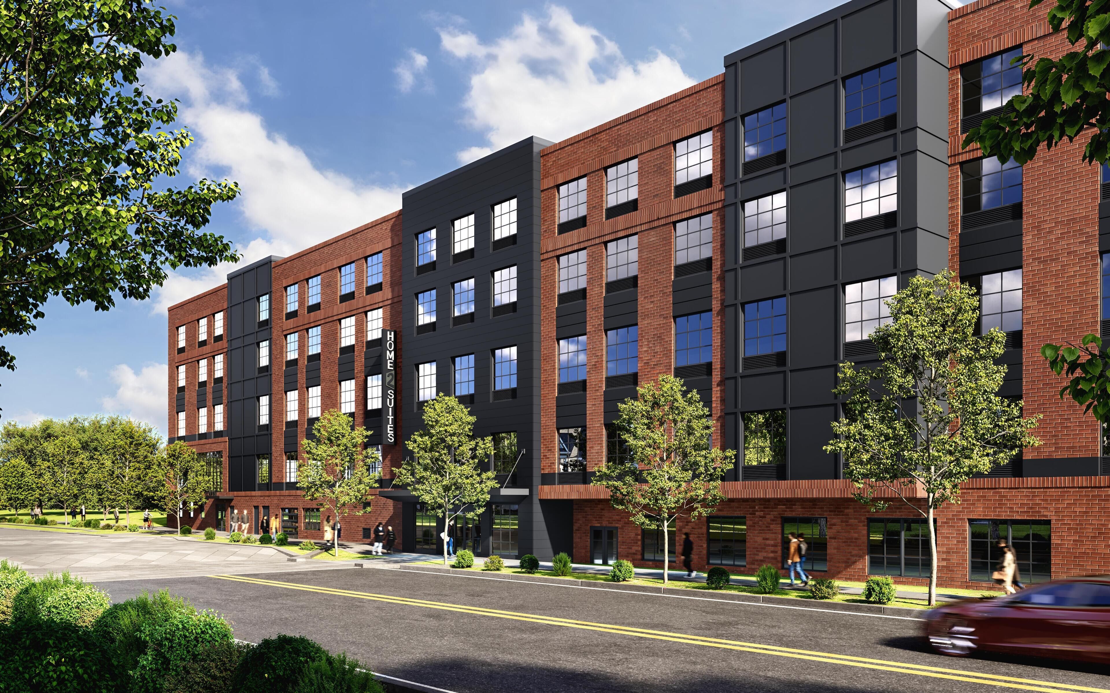 A modern multi-story building with a mix of brick and glass facades, featuring a prominent 'HOME SUITES' sign.