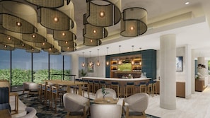 Espaço de bar moderno com pé direito alto, iluminação pendente em vime e balcão com uma grande tela exibindo esportes.