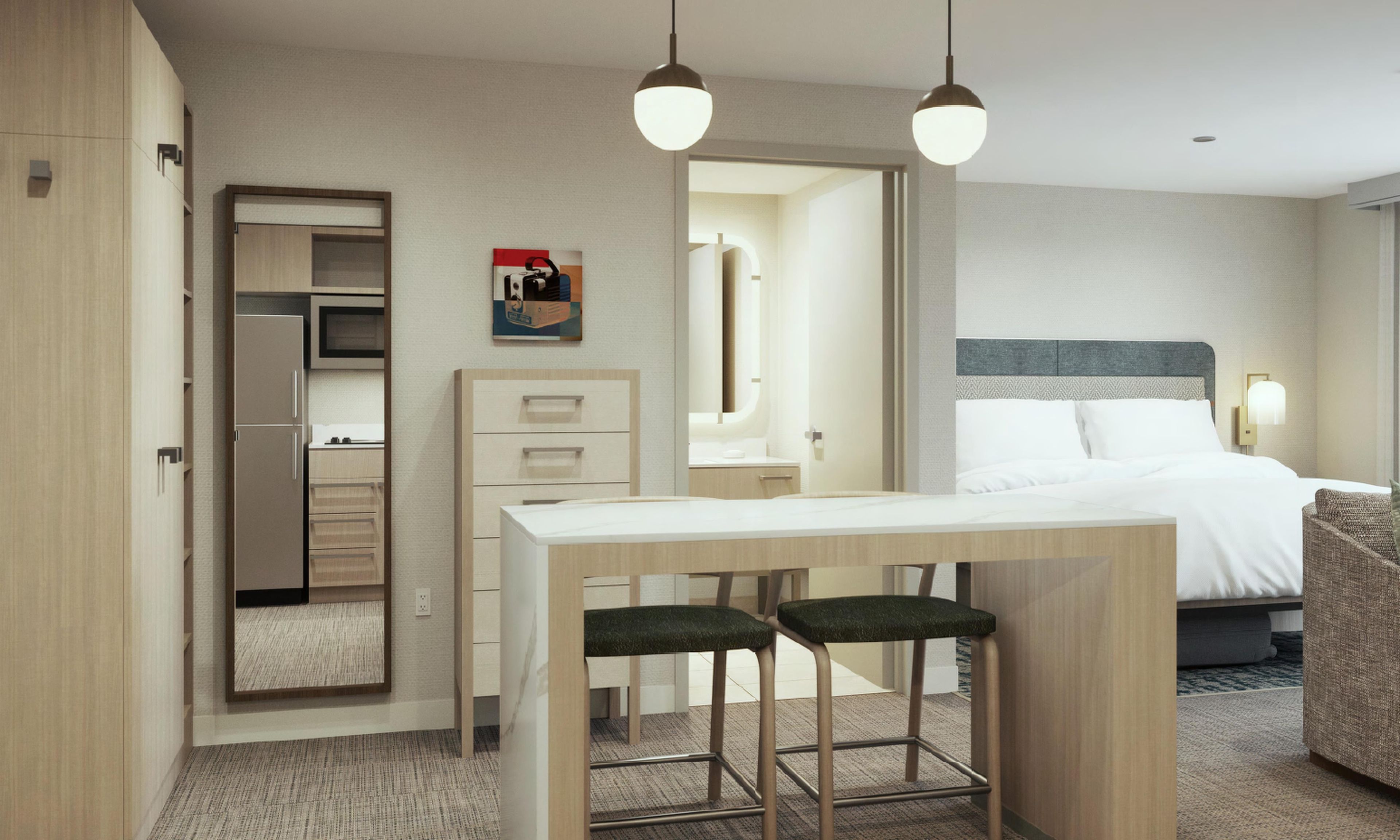 Quarto de hotel com cama, secretária com duas cadeiras, espelho e guarda-roupa.