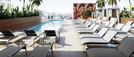 A rooftop pool area with lounge chairs and a city view.
