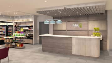 A modern hotel lobby with a reception desk, snack display, and a 'HOME 2' sign.