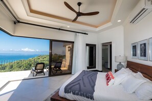 A bedroom with a large bed, a ceiling fan, and a view of the ocean. - Charming 3-bedroom estate in Osa • Private Pool • 180° Ocean View in Jungle (Puntarenas Province)
