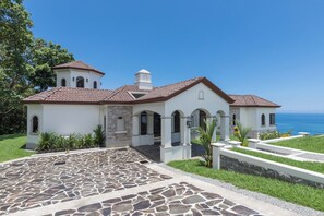A coastal property with a stone patio, white walls, and a view of the ocean. - Charming 3-bedroom estate in Osa • Private Pool • 180° Ocean View in Jungle (Puntarenas Province)