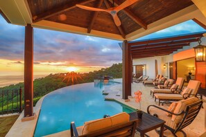A poolside area with lounge chairs and a view of the sunset over the ocean. - Charming 3-bedroom estate in Osa • Private Pool • 180° Ocean View in Jungle (Puntarenas Province)
