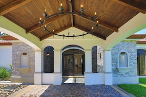 A covered entrance with a wooden ceiling and a chandelier, stone walls, and a tiled floor. - Charming 3-bedroom estate in Osa • Private Pool • 180° Ocean View in Jungle (Puntarenas Province)