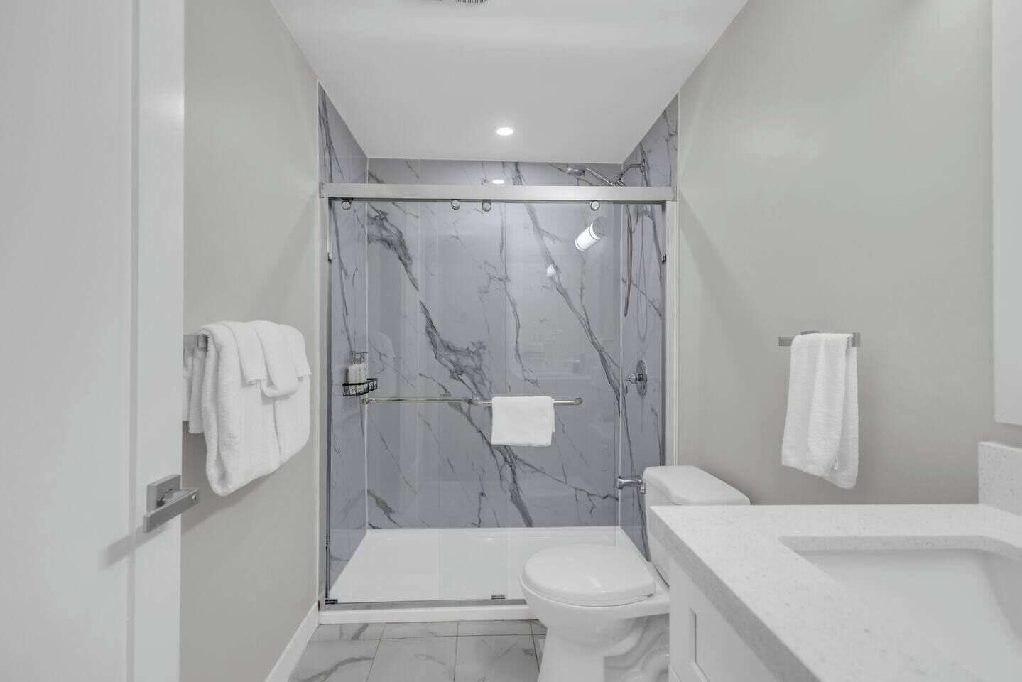 A modern bathroom with a glass-enclosed shower, a toilet, and a sink.