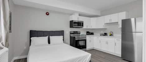 Une chambre d’hôtel moderne équipée d’un lit, d’une kitchenette et d’une lumière rouge de signalisation d’urgence.