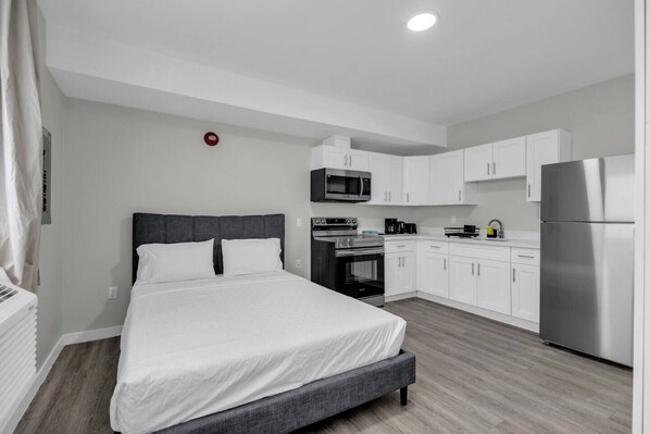 Habitación de hotel moderna con cama, kitchenette y una luz de emergencia roja.