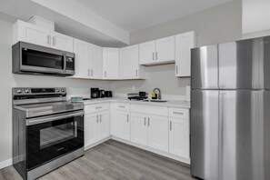 Une cuisine moderne avec des armoires blanches, des appareils en acier inoxydable et un plancher en bois.