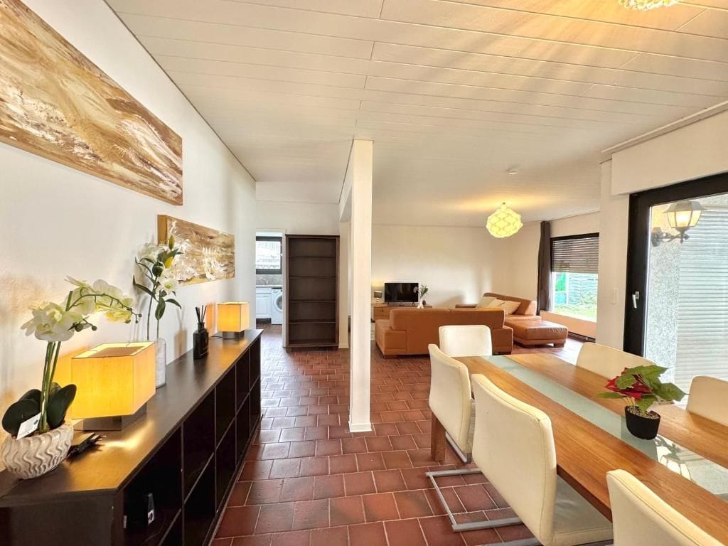 Una sala de estar moderna con comedor, chimenea y vistas al exterior.