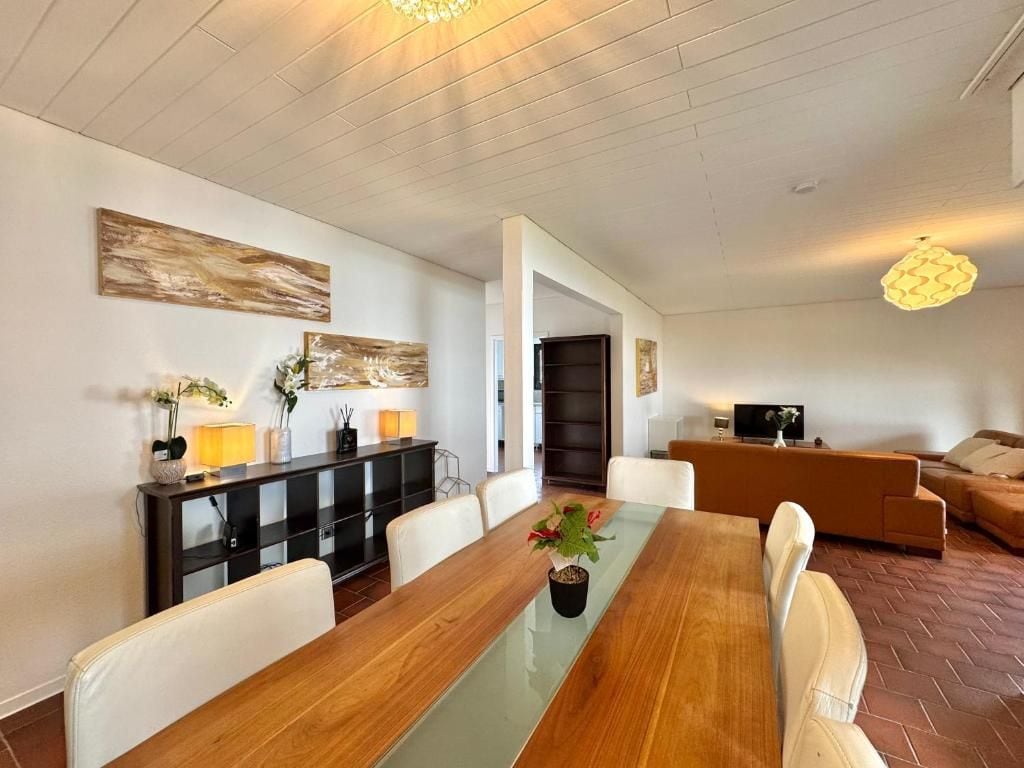 A modern living room with a dining table, sofas, and a TV.