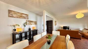 A modern living room with a dining table, sofas, and a TV.