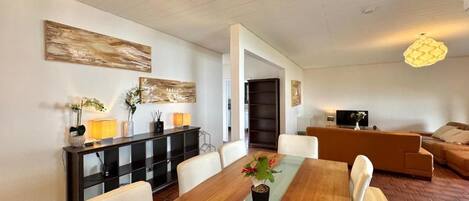 Una sala de estar moderna con una mesa de comedor, sofás y una televisión.