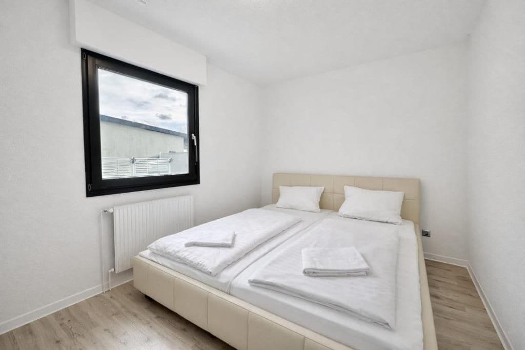 A small, clean room with a single bed, a window, and a radiator.