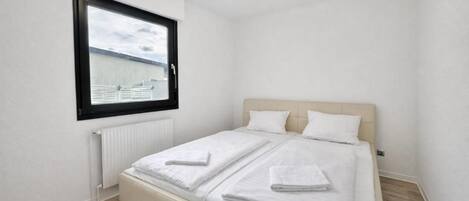 A small, clean room with a single bed, a window, and a radiator.