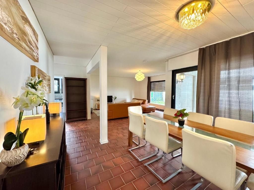 Una habitación de hotel con comedor, un sofá y una ventana con cortinas.