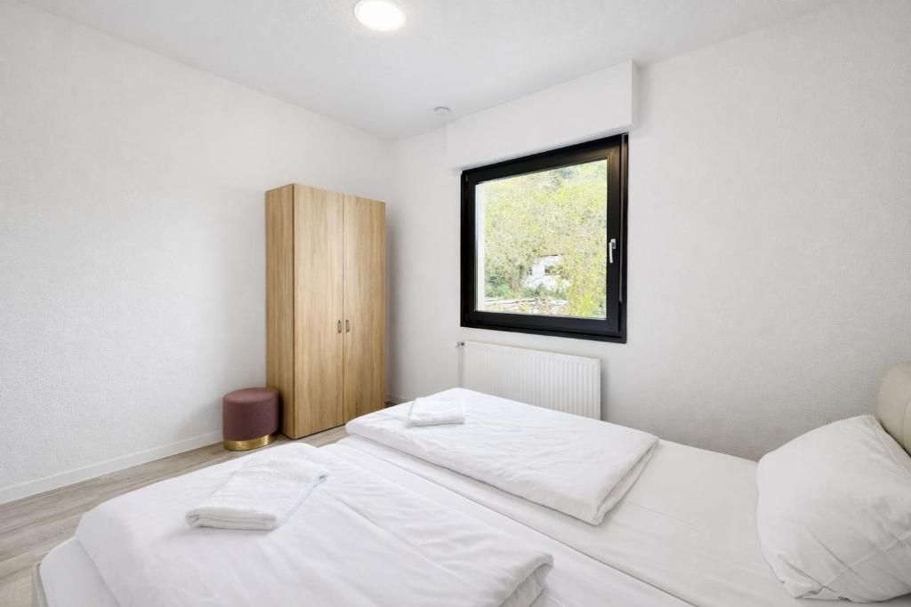 A bedroom with two beds, a wardrobe, a window, and a radiator.