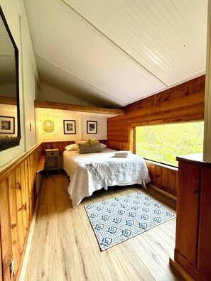 Una camera da letto con un letto, comodini, un tappeto e una finestra vista.