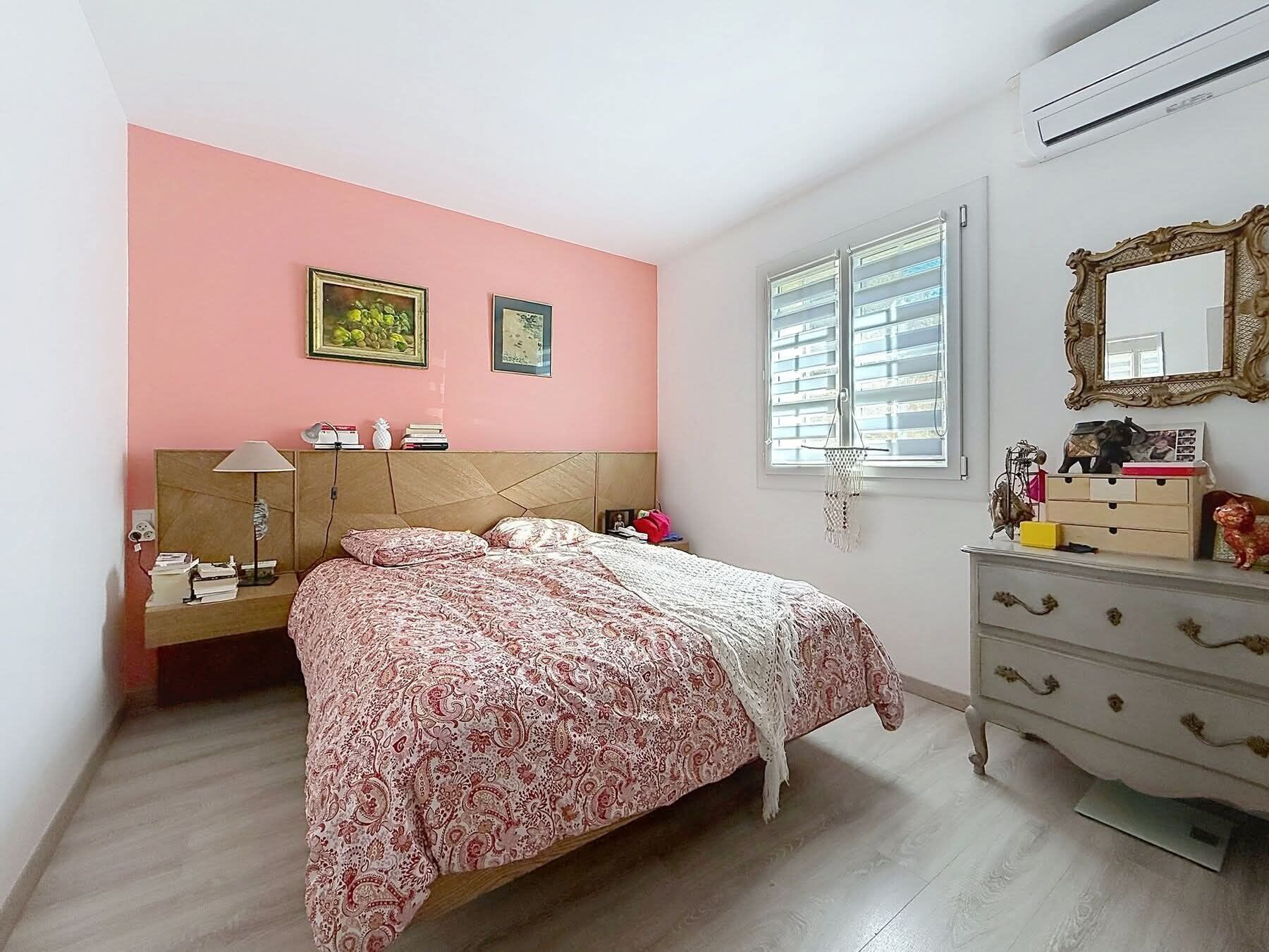 A bedroom with a bed, dresser, two paintings, and a window with blinds.