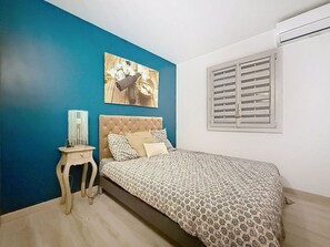 A bedroom with a bed, a nightstand, a wall-mounted picture, and a window with shutters. - Charming Provençal house with a private pool (Monteux)