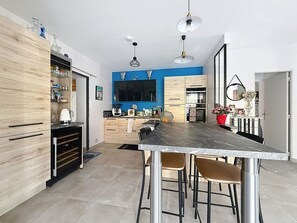 A modern kitchen with a central island, wooden cabinets, and a dining area with bar stools. - Charming Provençal house with a private pool (Monteux)