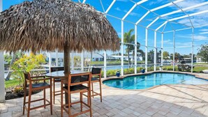 Área da piscina com um espaço de estar coberto e vista para a piscina.