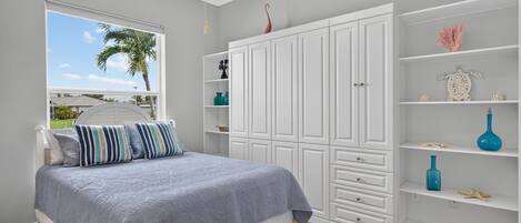 Une chambre à coucher comprenant un lit, une armoire et une étagère avec des objets décoratifs.