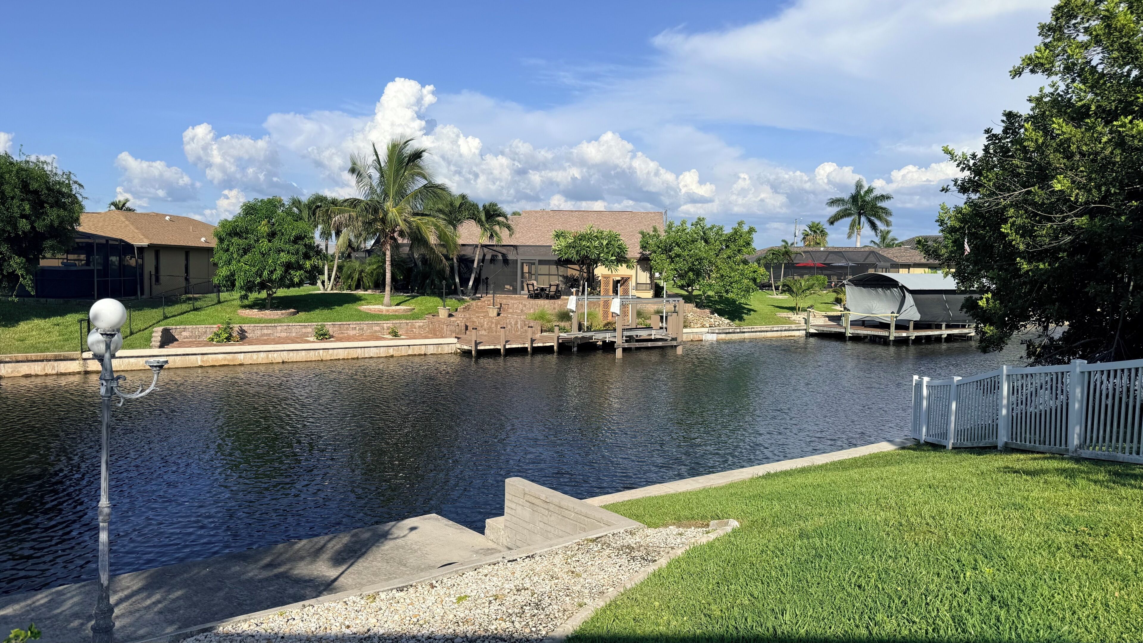 A residential area with a water body, a dock, and houses in the background.