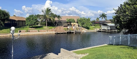 A residential area with a water body, a dock, and houses in the background.